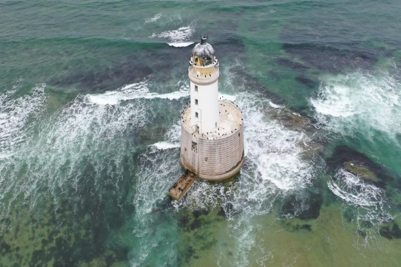 a lighthouse on top of some green and white water