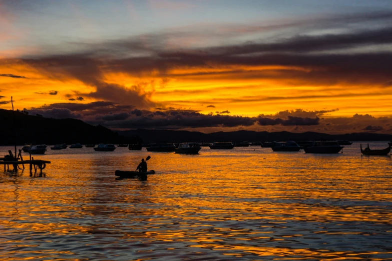 a sunset with clouds over boats on a lake