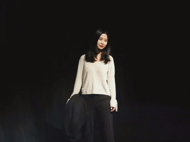 a woman posing in a black studio in front of black background