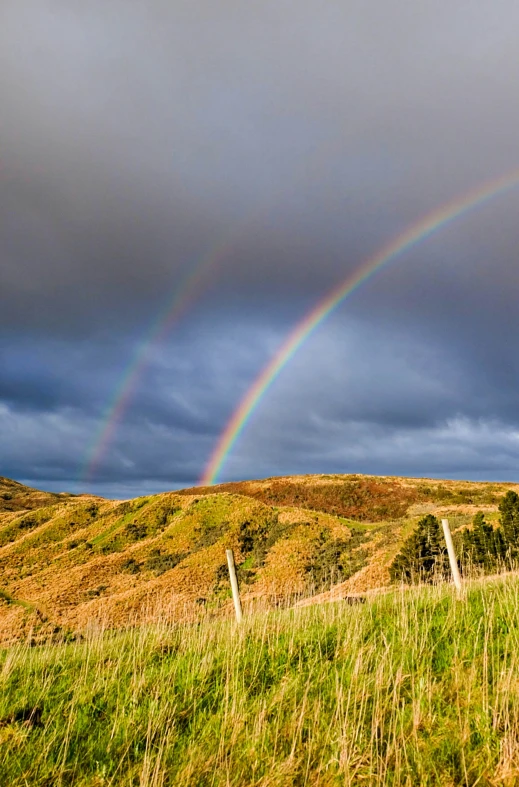 a rainbow in the distance with a cloud covering the sky