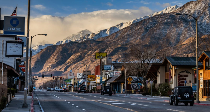 a mountain range towering over a street with buildings on both sides