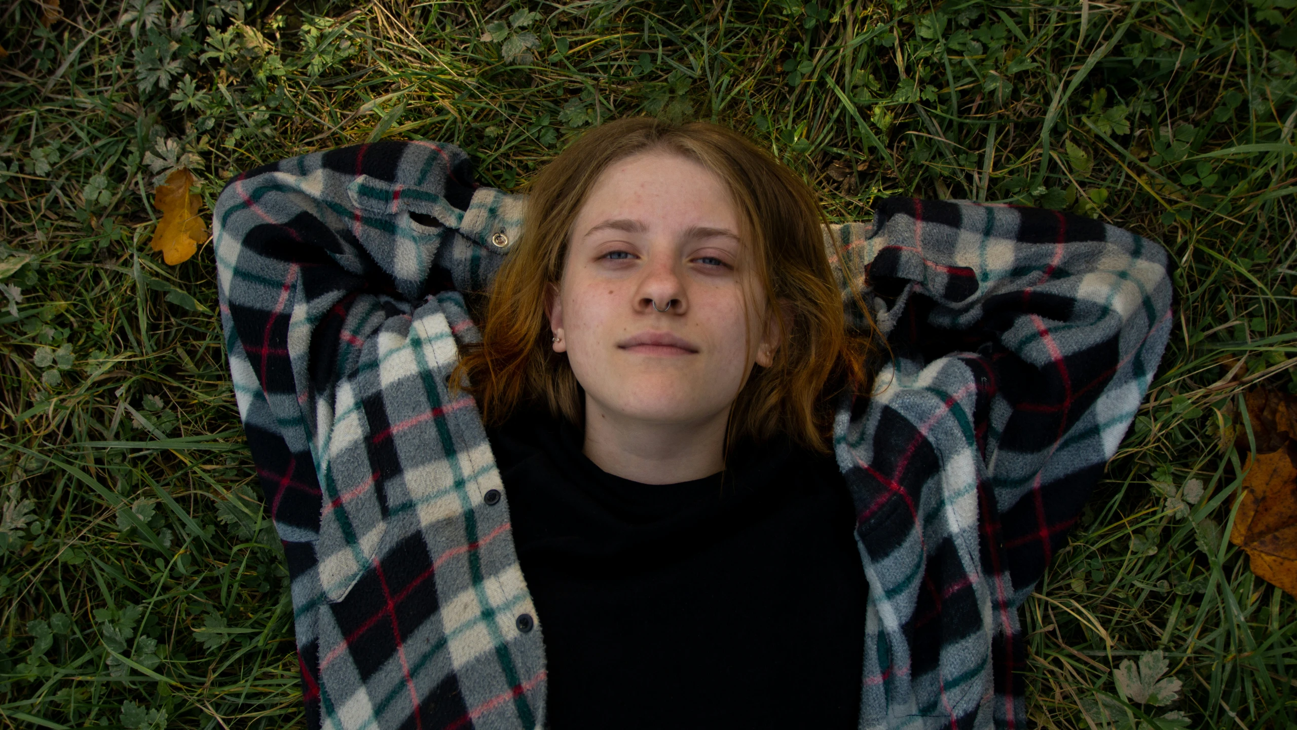 a girl laying on the grass with her eyes open