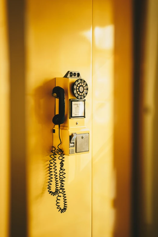 a yellow phone and two bells on a white wall