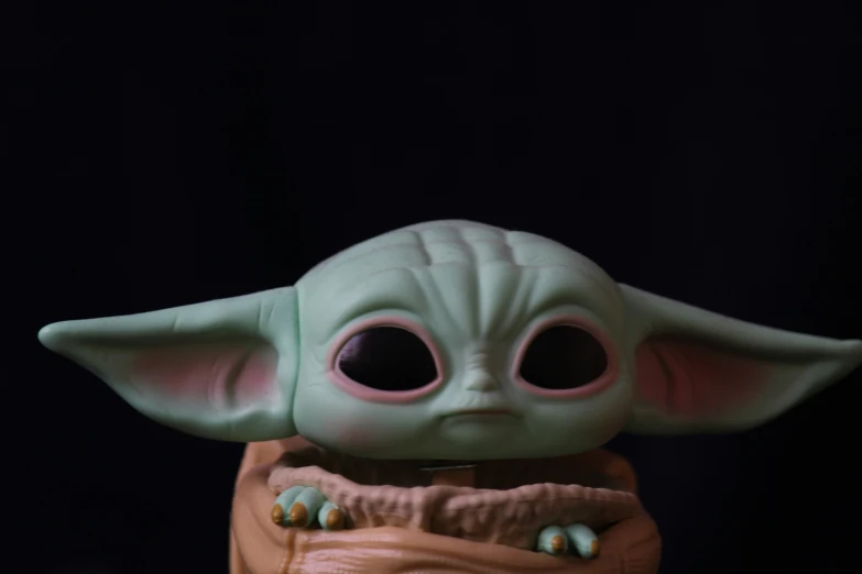 a baby yoda doll holding its tongue out