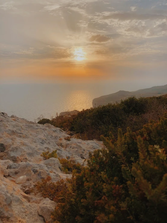 the sun sets over an area with rocks and trees