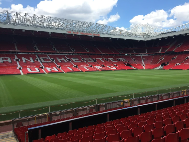 empty stadium with red seats and a green field