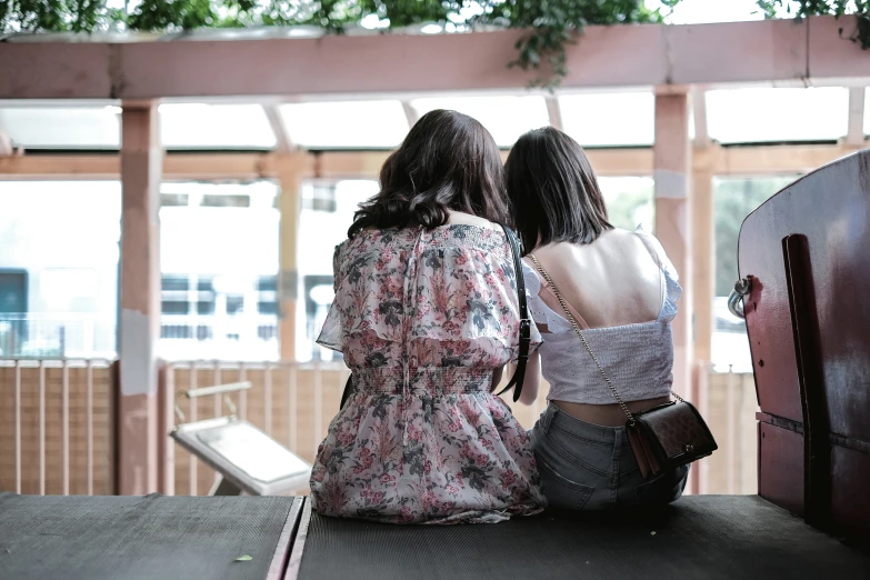 two women sitting next to each other on top of a roof