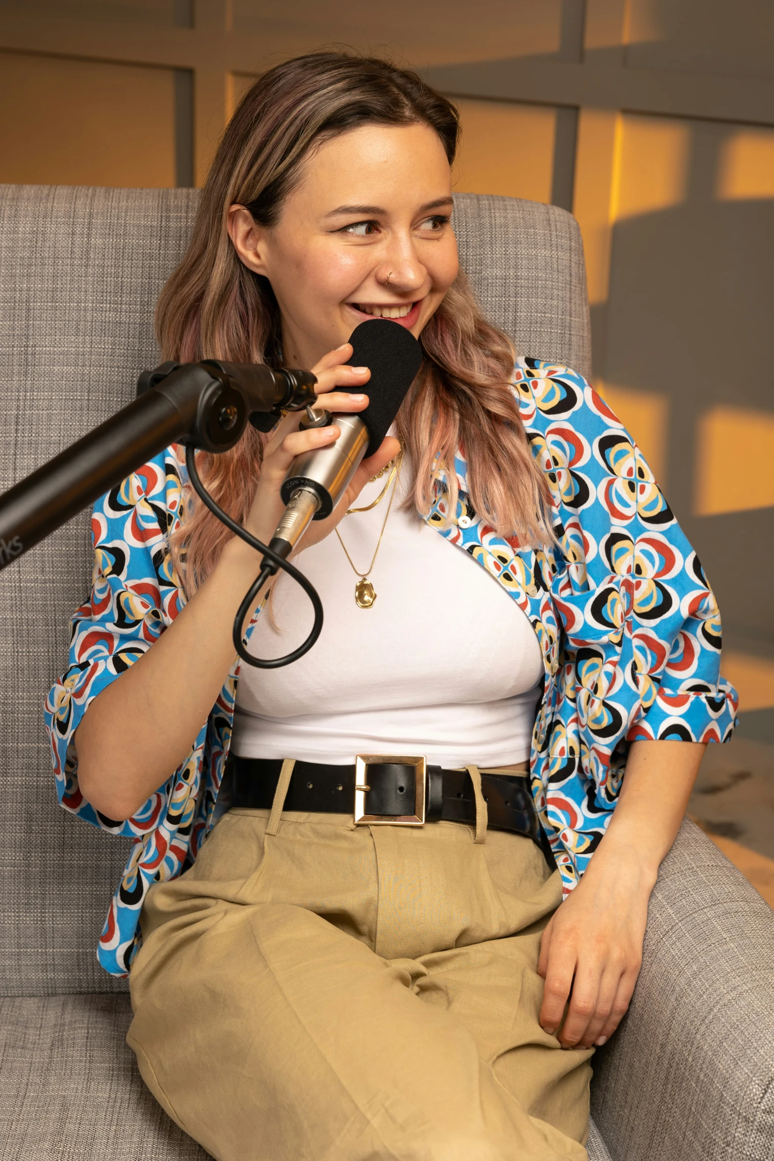 a girl sitting in a chair holding a microphone and talking on a phone