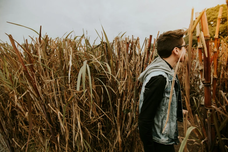 a man stands in tall grass, making a creepy face