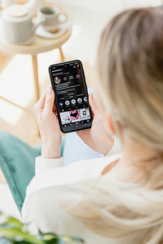 woman in white shirt holding up an electronic device