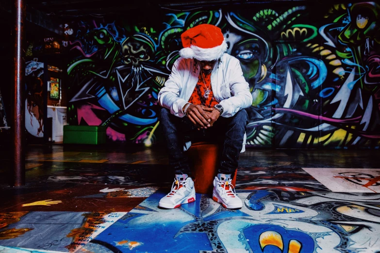 a man sitting on top of a floor next to a wall covered in graffiti