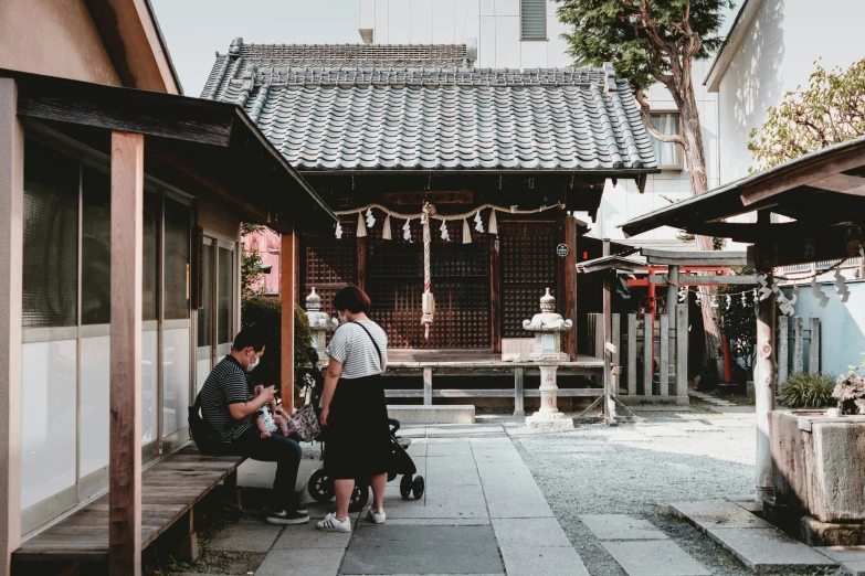 three people standing in the shade of an older building