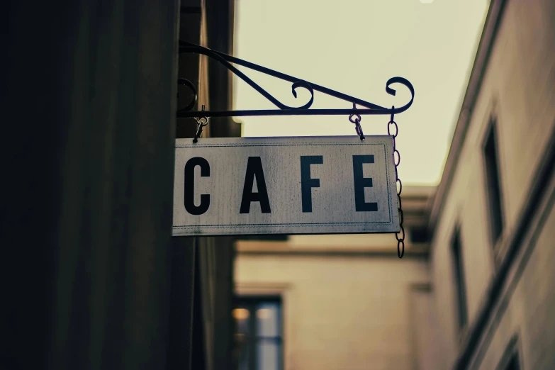 the sign hanging from a building reads cafe
