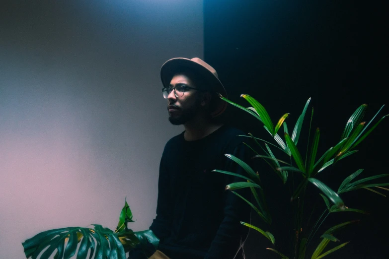 the man is standing by a potted plant in his house