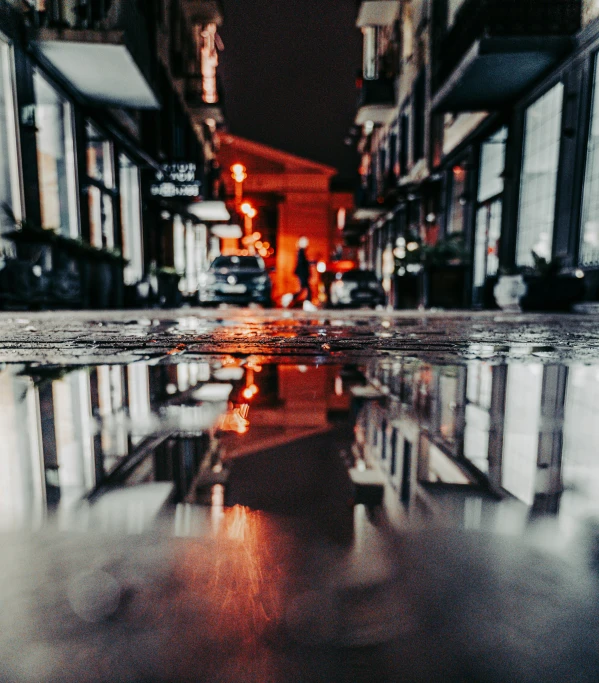 a street view with an umbrella reflected in the wet pavement