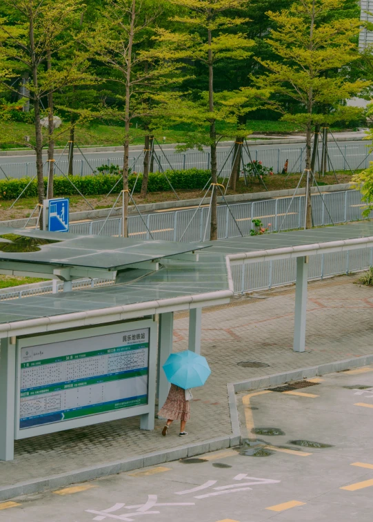 a woman walking under an umbrella in front of an empty road