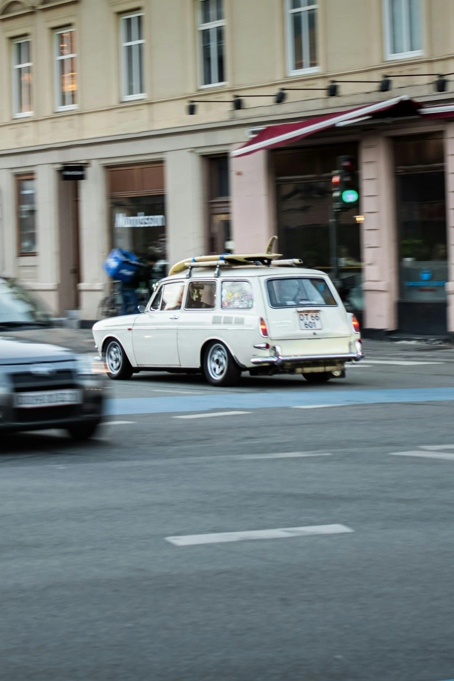 a small van with surfboard strapped on top traveling down the street