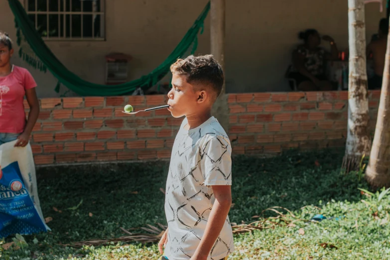 a boy standing in front of a building holding a tennis ball