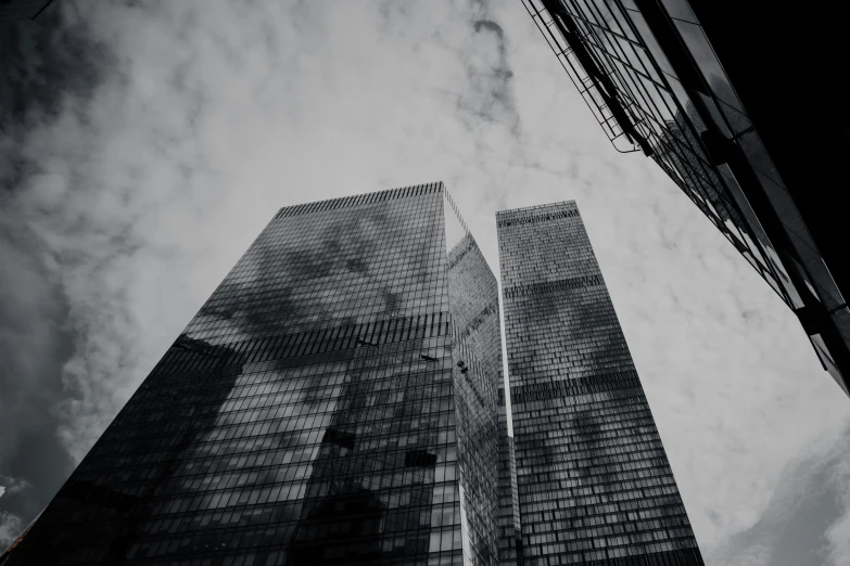 two skyscrs in an urban area with clouds