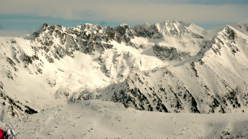 two people on skis standing near a very large mountain