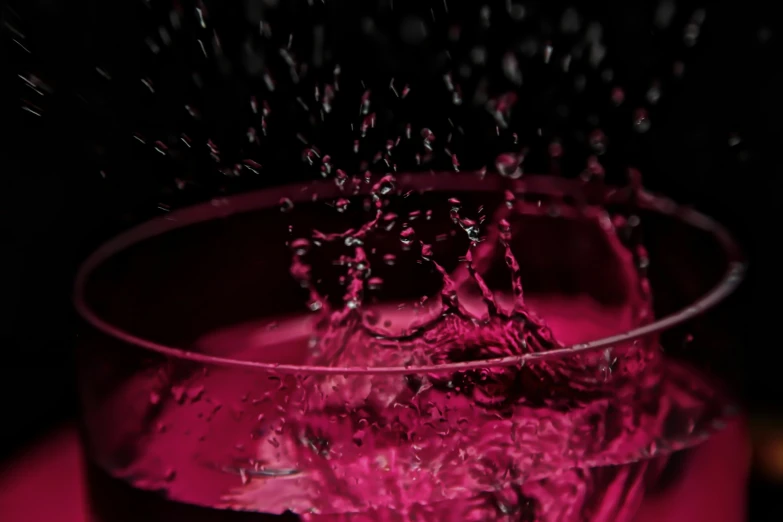 water being spewed into a glass of red liquid