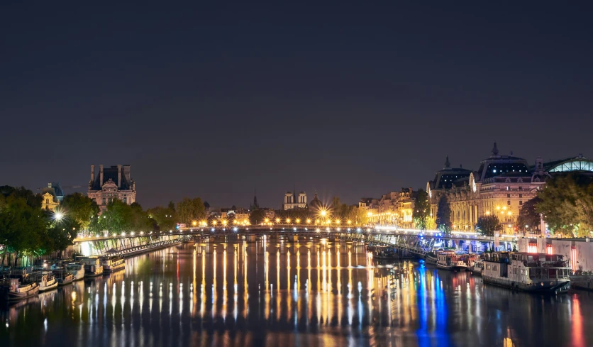 a night time scene with a waterway with boats and a bridge