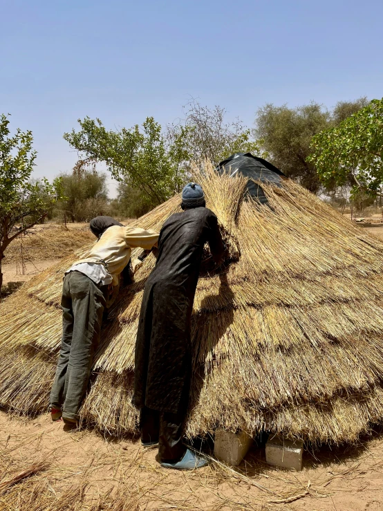 a couple of people standing on top of a hay covered field