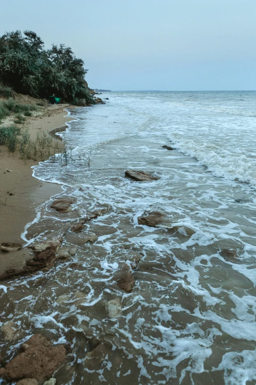 a beach with some waves coming in and a boat on it