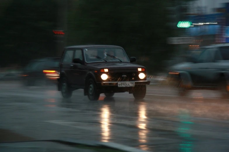 a jeep driving in the rain down a street