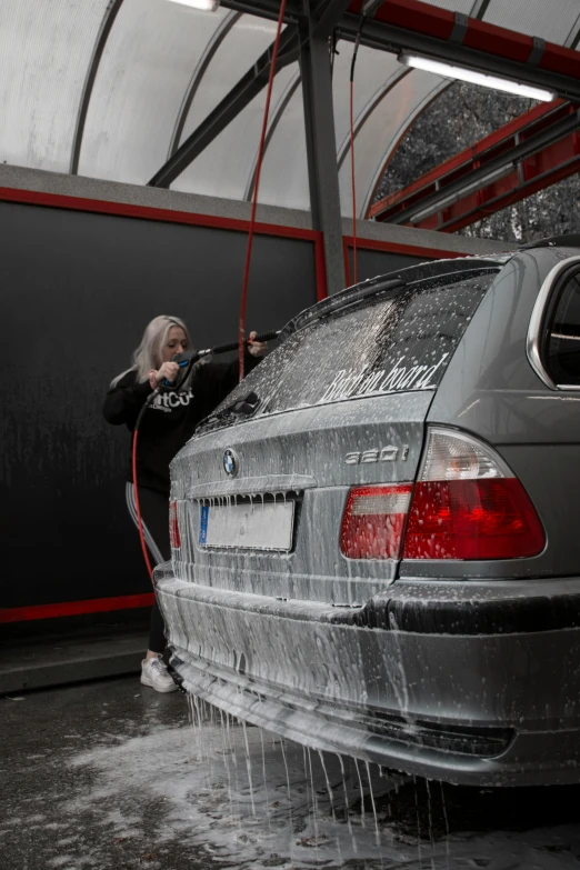 a woman washing her car with an electric shower