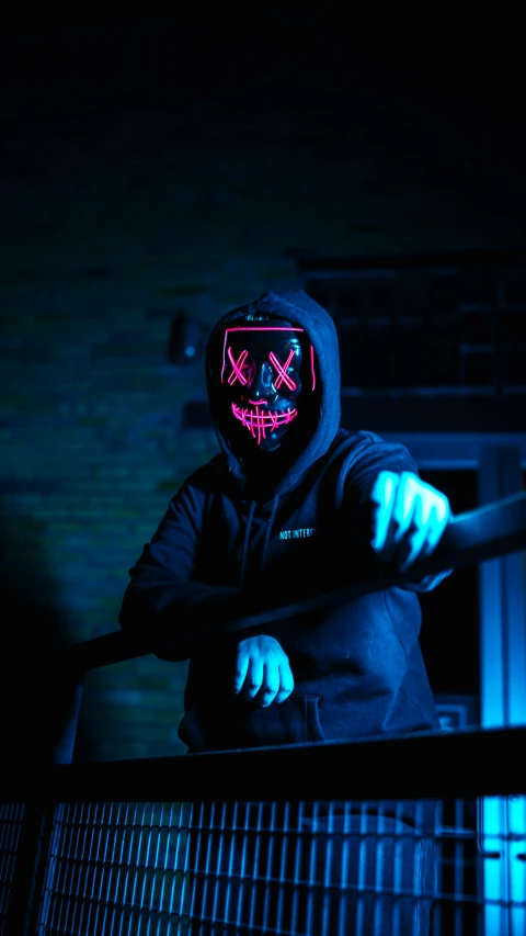 a man in a neon mask stands on a rail