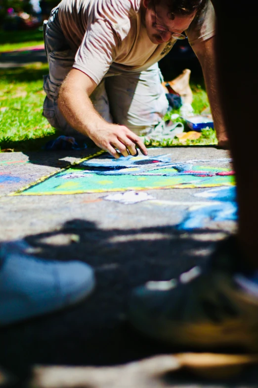 a person is using sidewalk paint to draw on a sidewalk