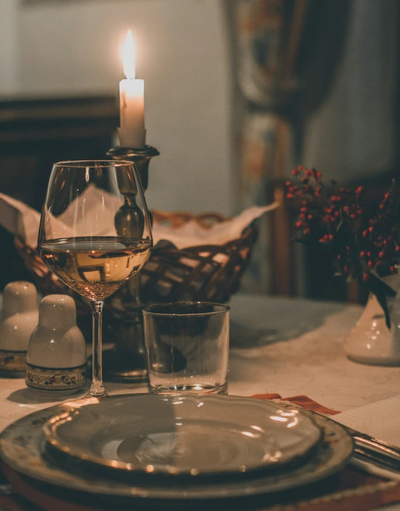 a place setting with white wine and a candle