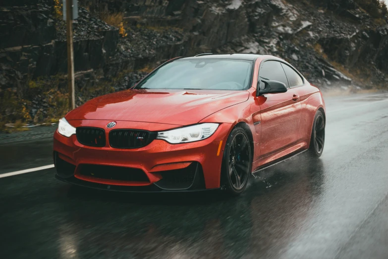 a red bmw in the road on a rainy day