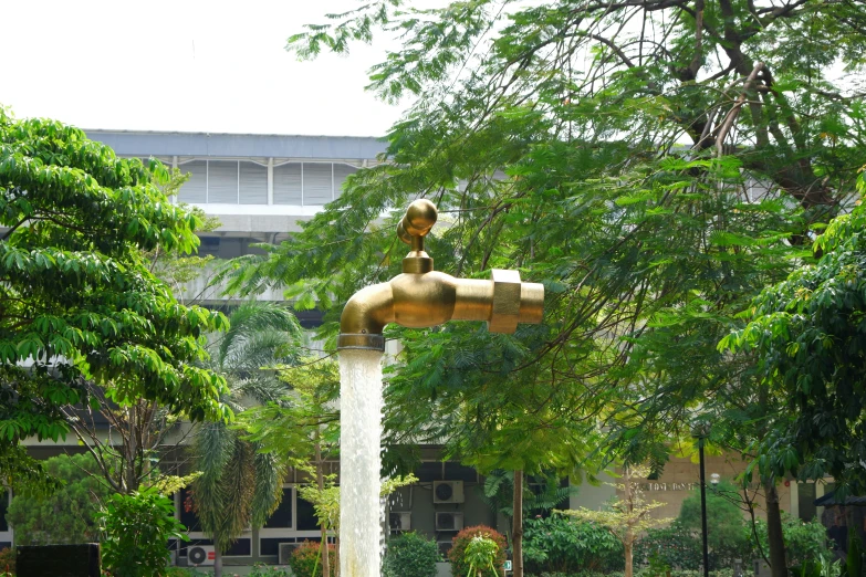 a large yellow faucet fountain surrounded by trees