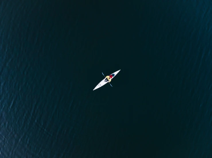 a small boat floating in the water next to a man