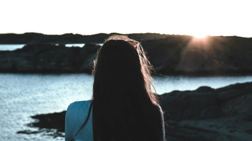 a girl looking into the distance from over looking a lake