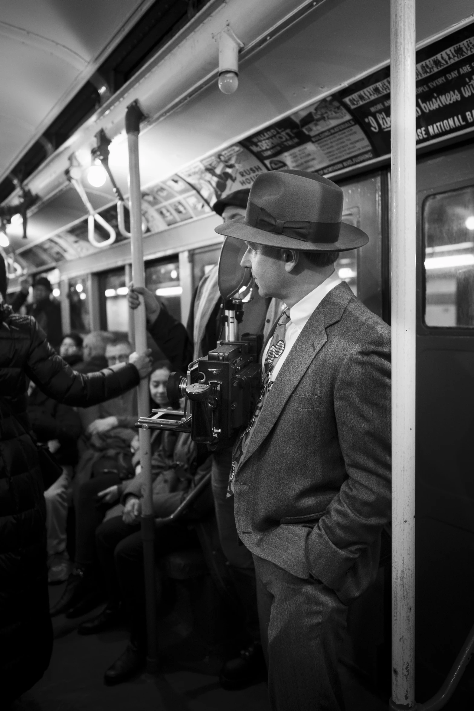 a man in suit and fedora standing by the door on a subway