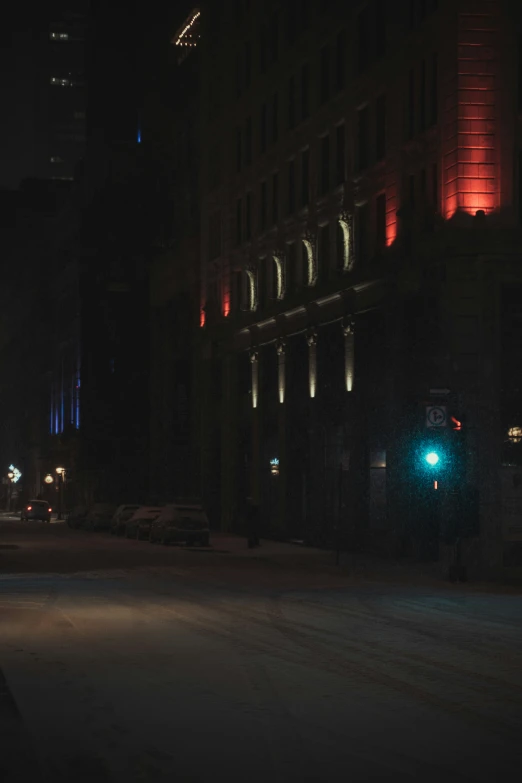 the city street is dark and has green traffic light