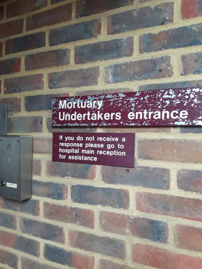 a brick wall with a sign posted above it reading'honorary - underneathfakes entrance '