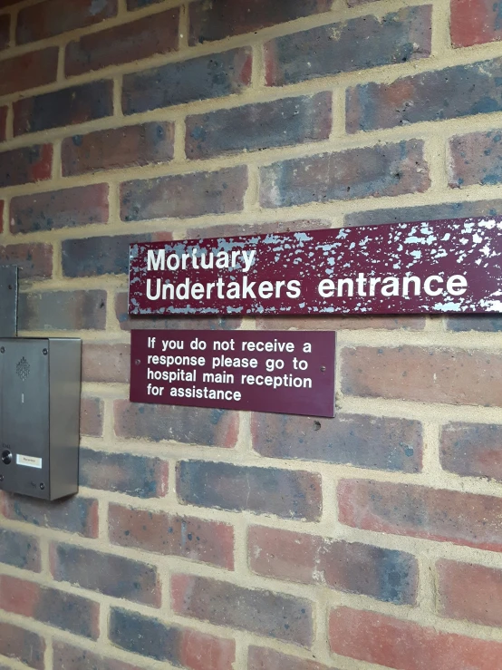 a brick wall with a sign posted above it reading'honorary - underneathfakes entrance '