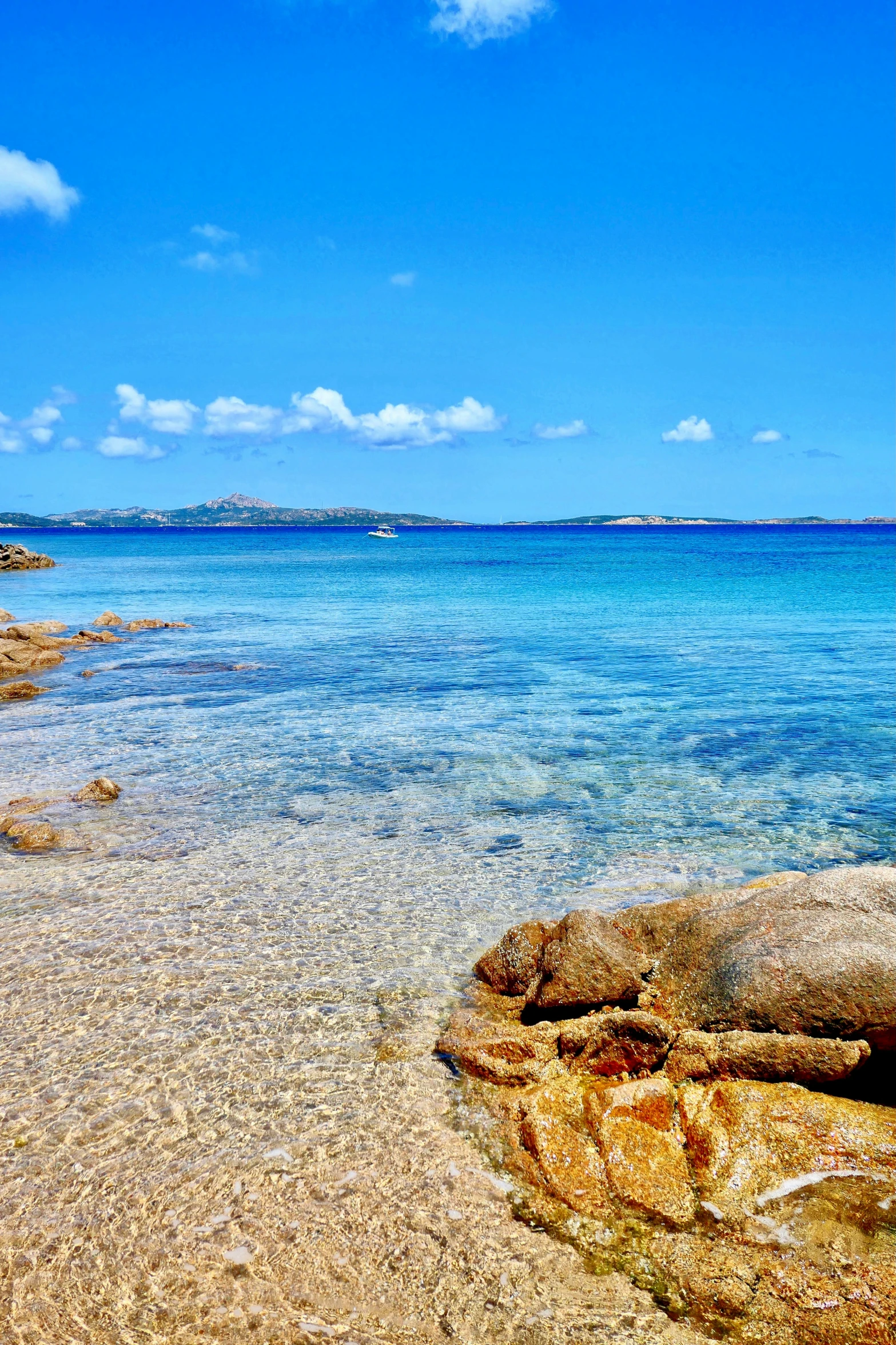 a beach has a clear blue sky with some white clouds