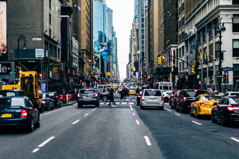 a busy city street with traffic, a person riding a bicycle and several cars parked on it