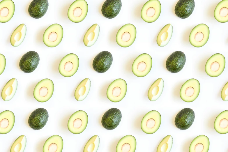 several small avocados arranged together in rows on white