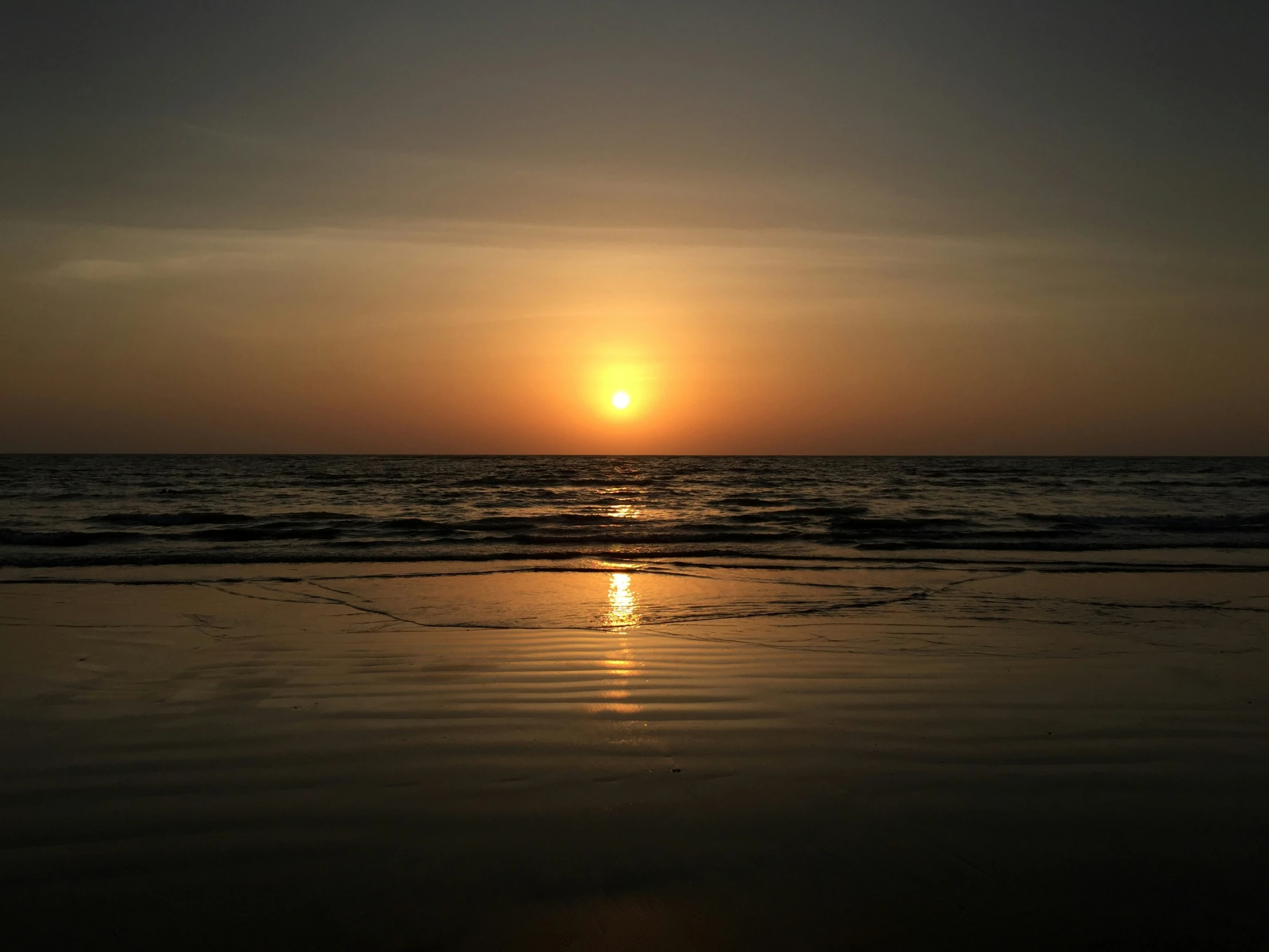 the sun setting over the ocean on the beach