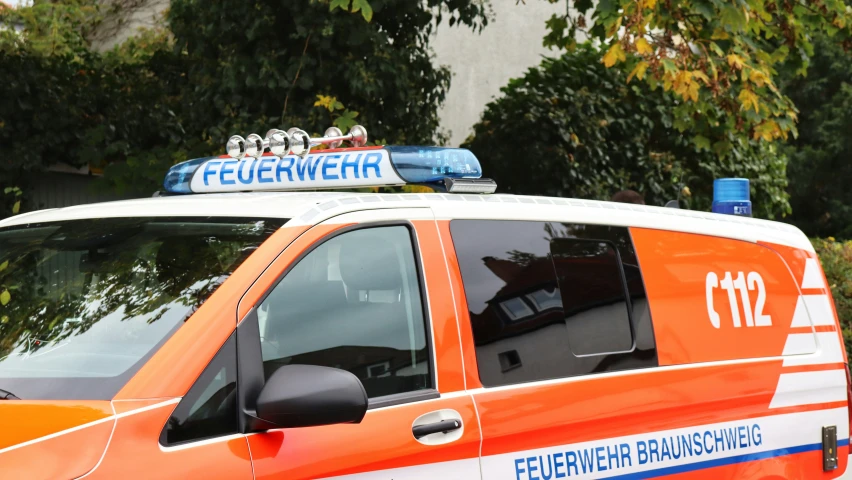 the side of a parked orange and white ambulance