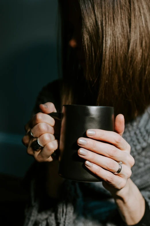 a close up of someone holding a cup with a engagement ring