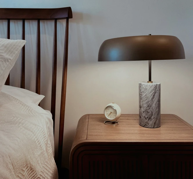 the bedside table has a clock and small round object on it