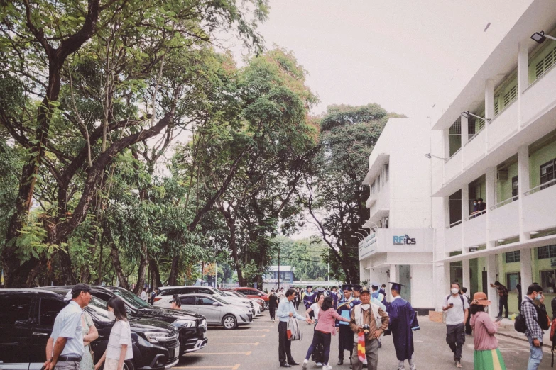 many people in parking spaces with parked cars