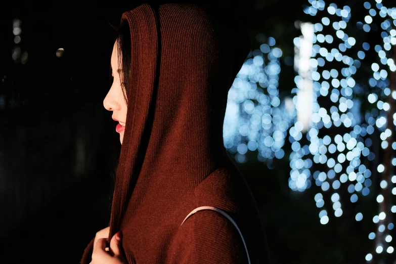 a woman with red hooded jacket looking at a building that has christmas lights all over it